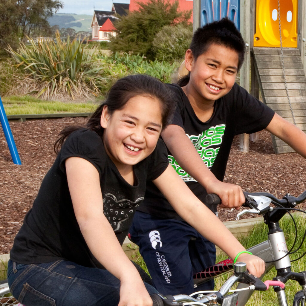 Brother and sister on bikes at playground